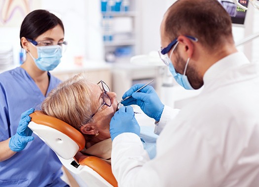 A dentist and hygienist examining a patient’s smile during a consultation 