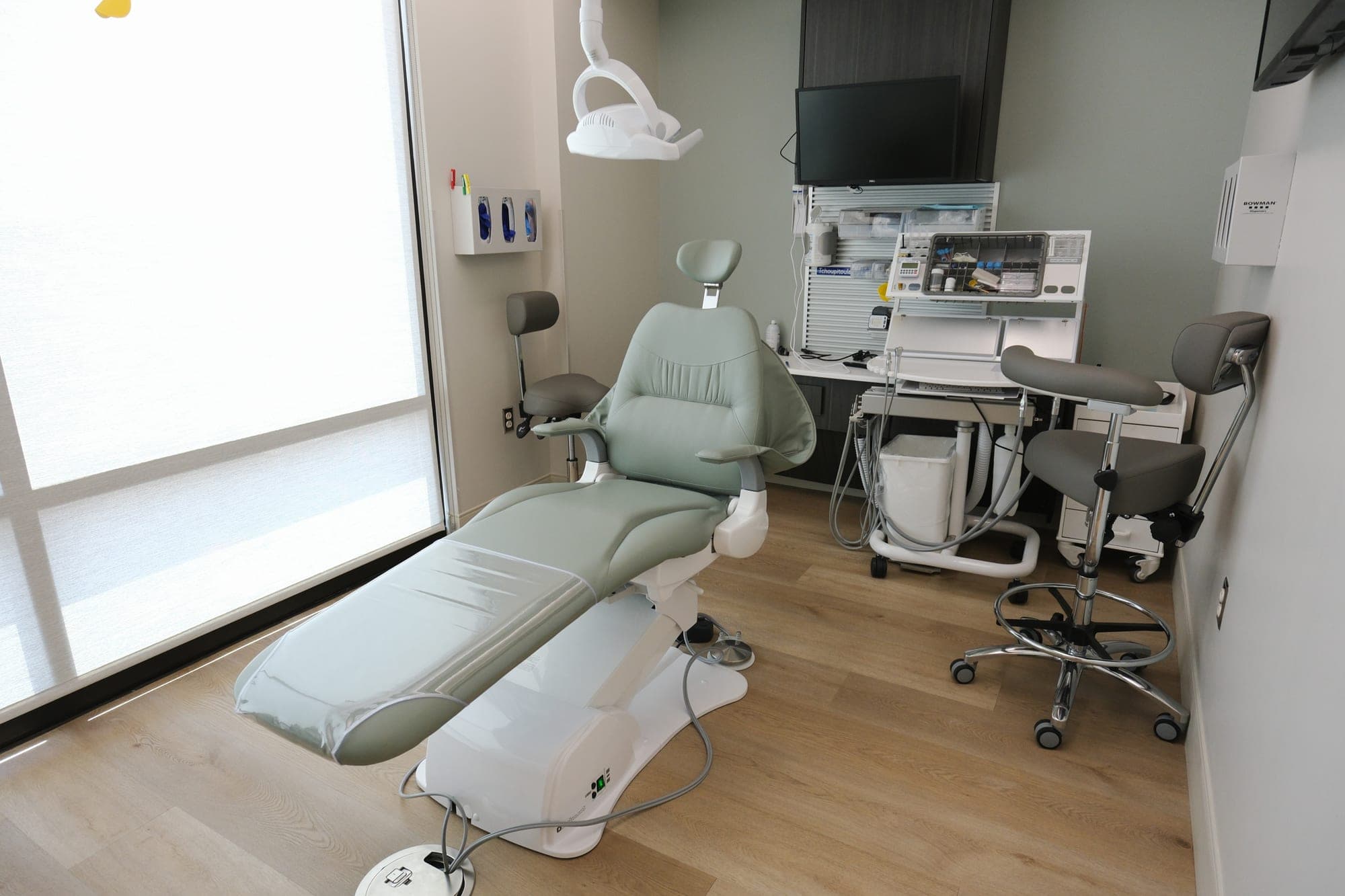 A treatment room set up for chairside digital scanning, lit by the window wall