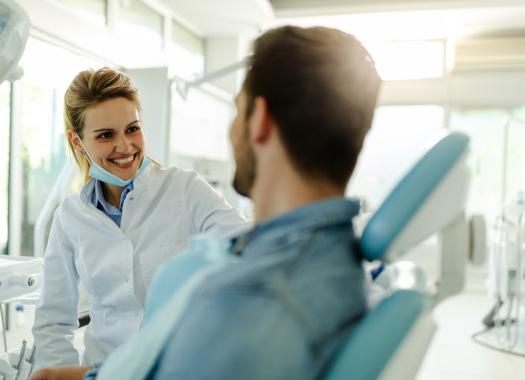 Smiling dentist talking to patient in treatment chair