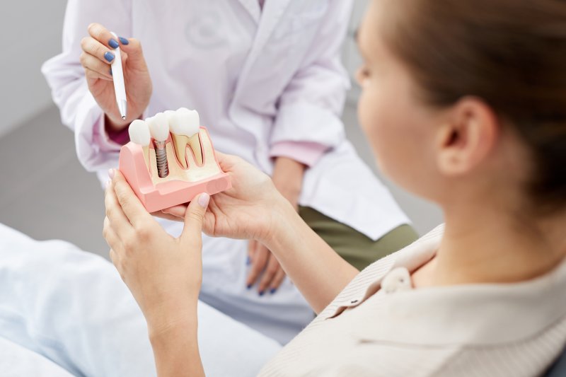 a patient holding onto a model of dental implants