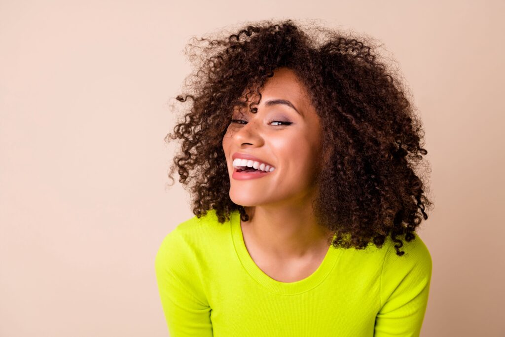 3/4 profile view of woman in yellow-green sweater smiling